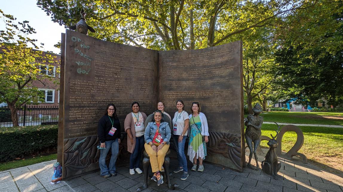 Six ARSL conference attendees posing in front of a huge statue of a book.