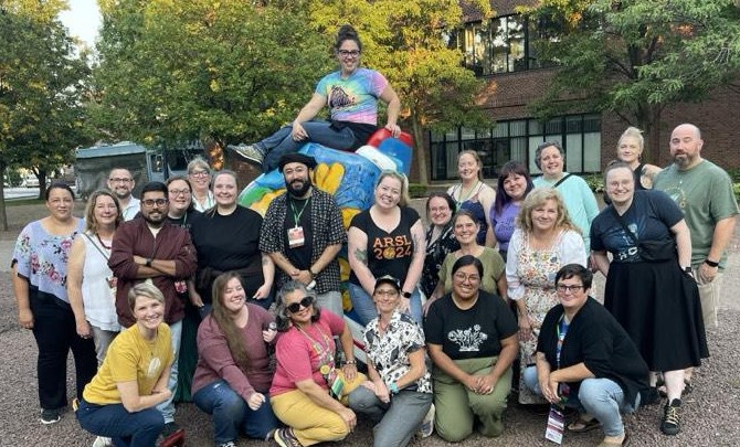 Group of ARSL conference attendees posing around a statue in a courtyard.