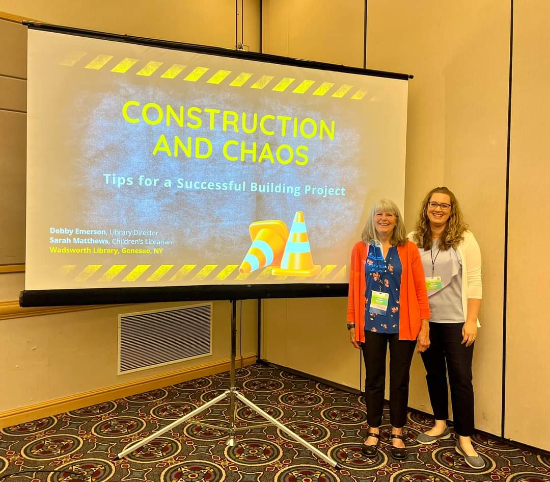 Two ARSL speakers in front of a screen with "Construction and Chaos" projected on it.
