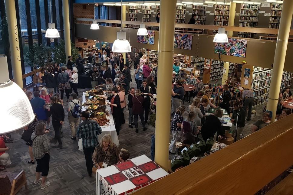Attendees milling around the opening ARSL conference reception in a library.