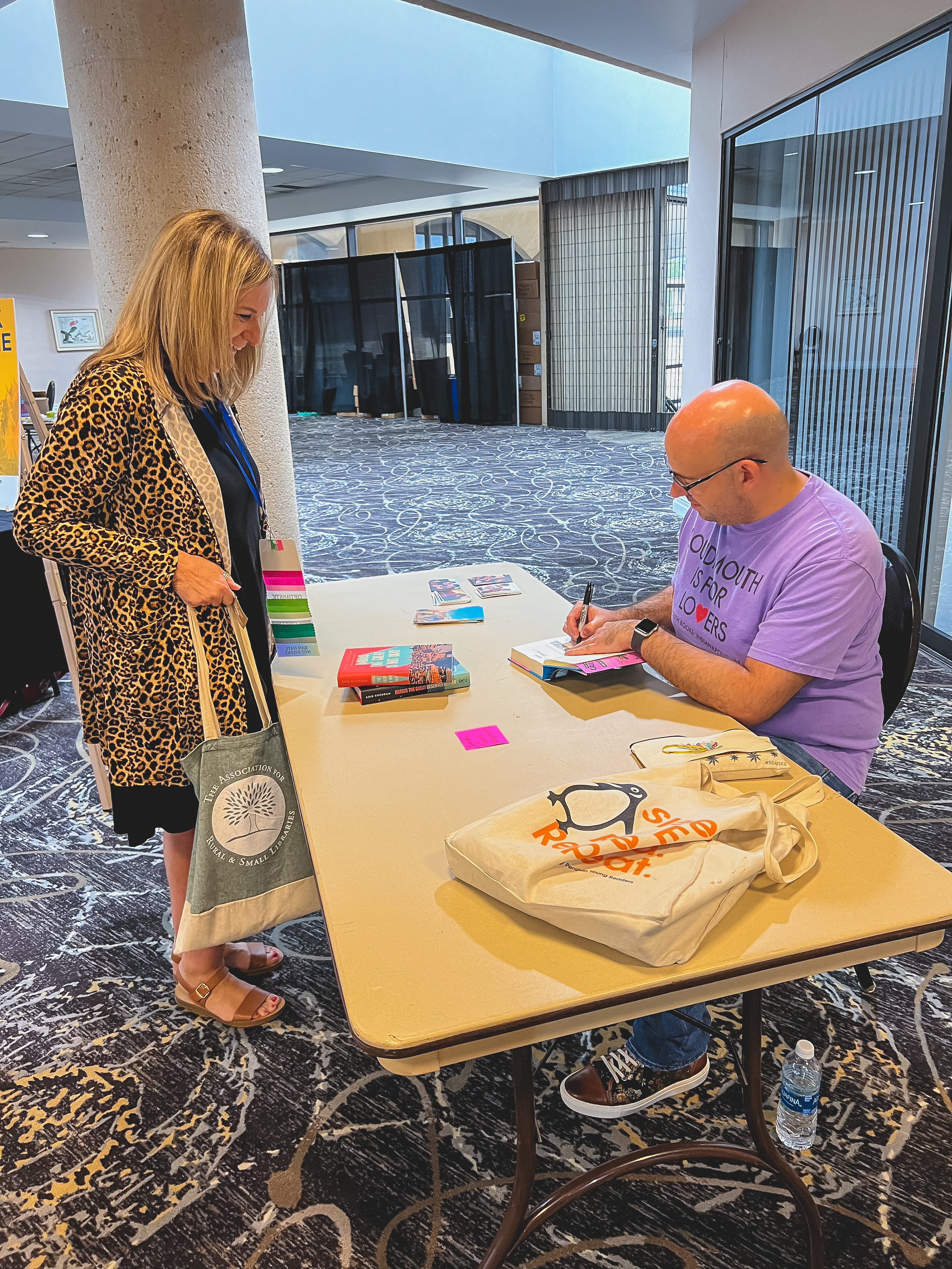 Grinning ARSL conference attendee getting a book signed by a seated author.